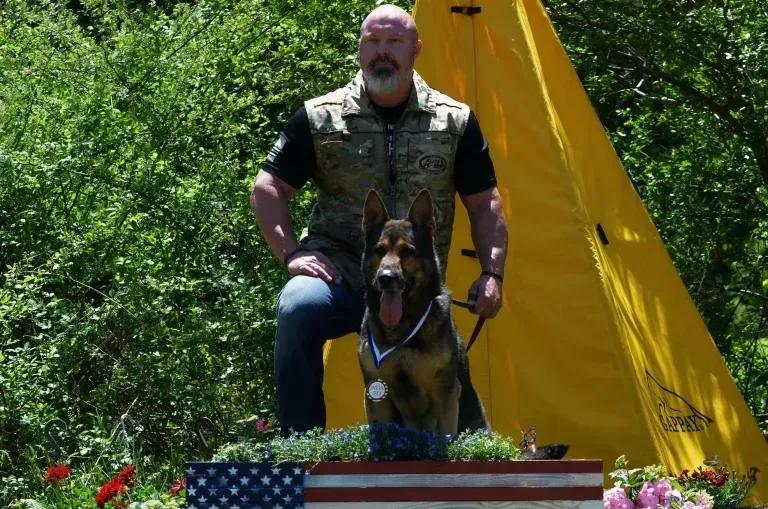 Justin Rigney with a German Shepherd wearing a medal on a decorated award stand
