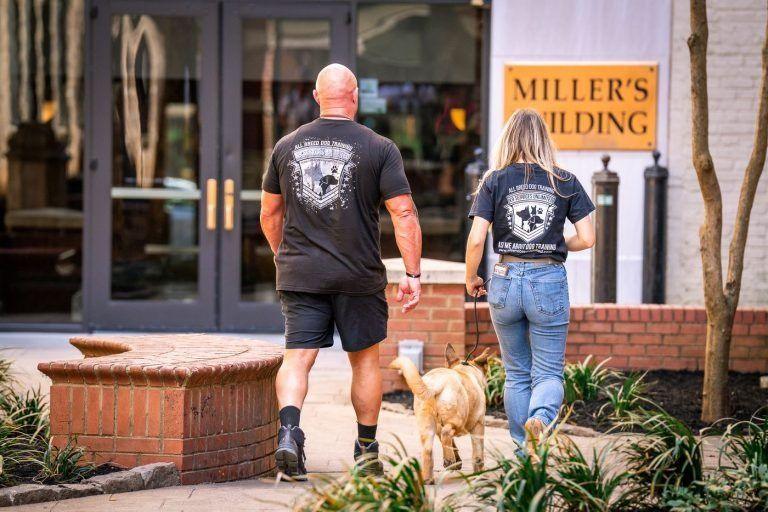 Trainers and a dog walking toward the Miller's Building entrance in downtown Knoxville, TN