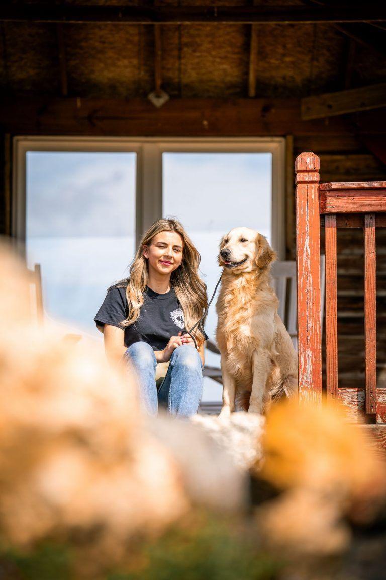 Woman and golden retriever sitting in a rustic doorway