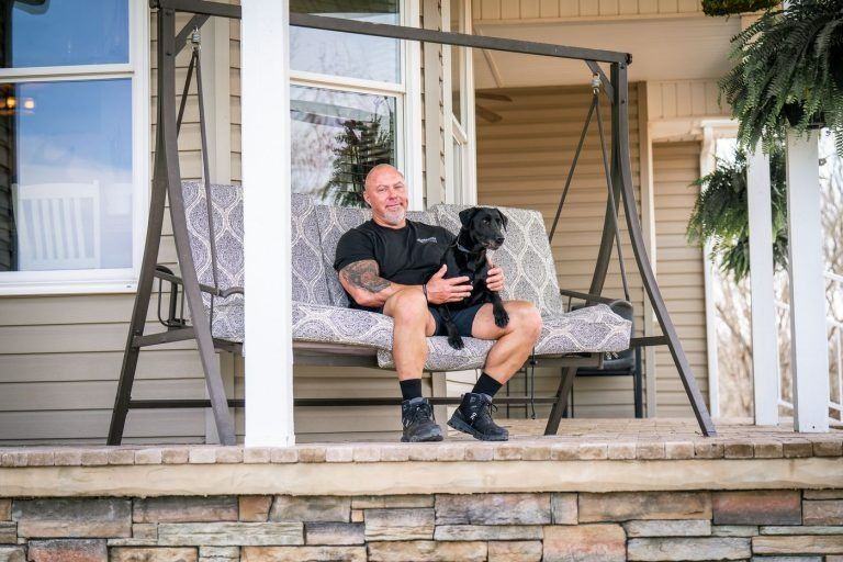 Black dog practicing obedience on a porch