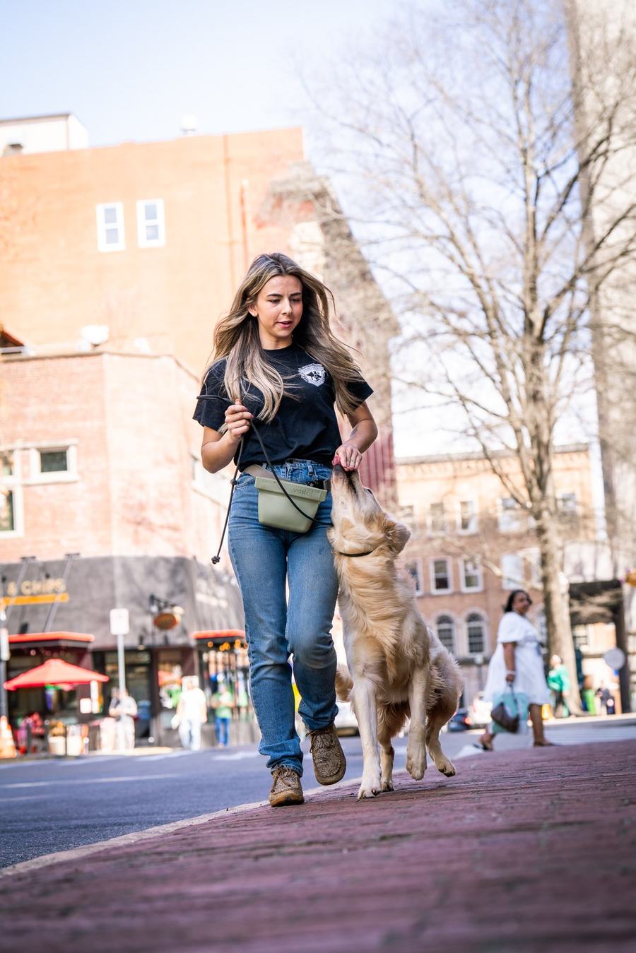 Rebeka walking a golden retriever through downtown Knoxville